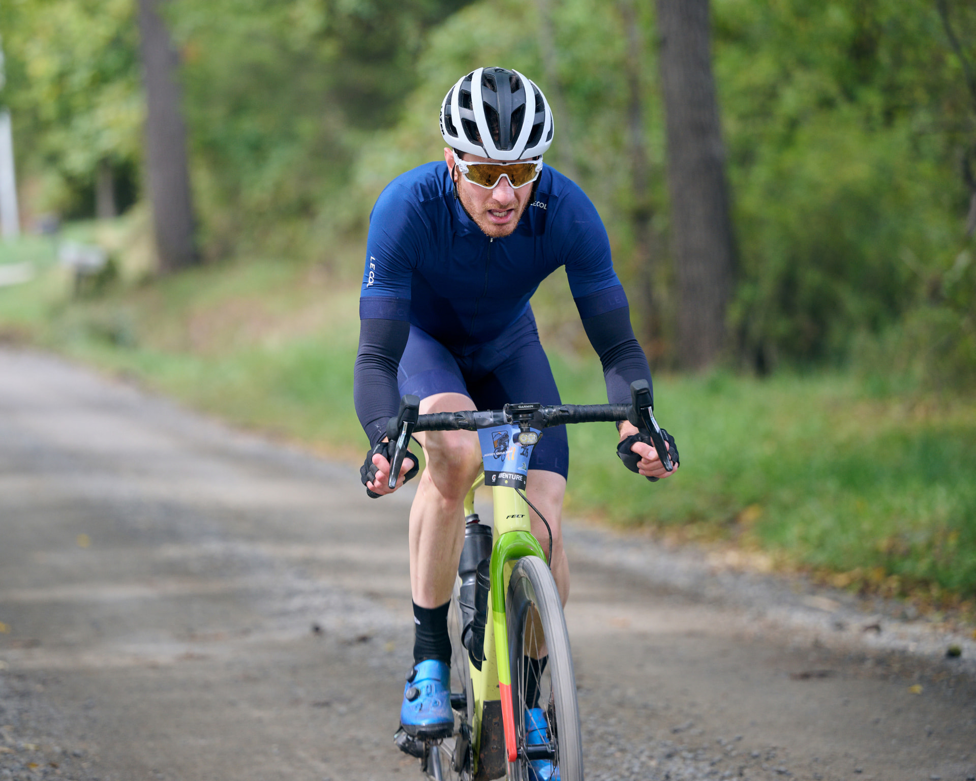 Gravel racer in a blue kit driving up a dirt road