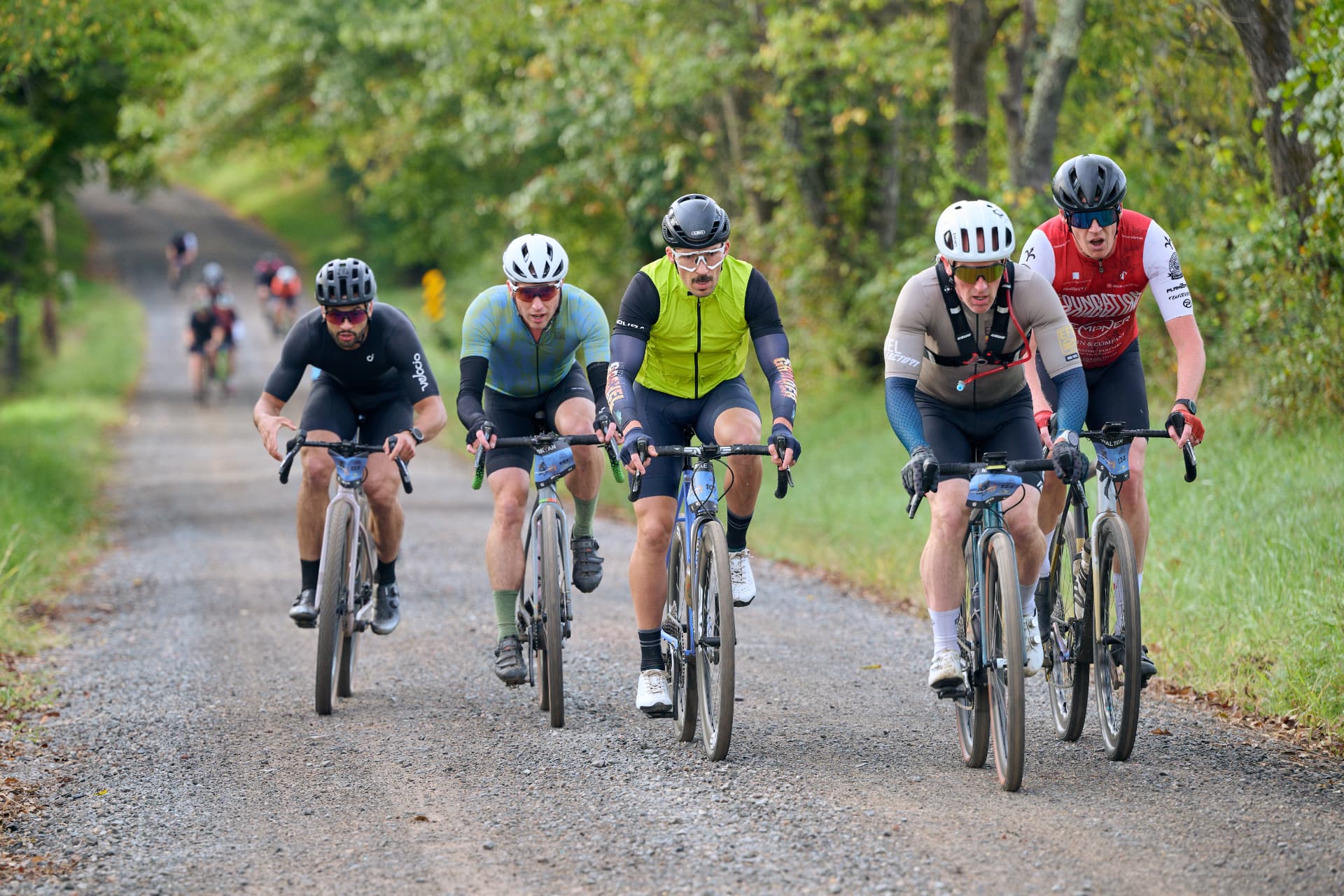 Five riders side by side on a dirt road
